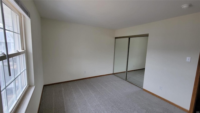 unfurnished bedroom with carpet, baseboards, and a closet