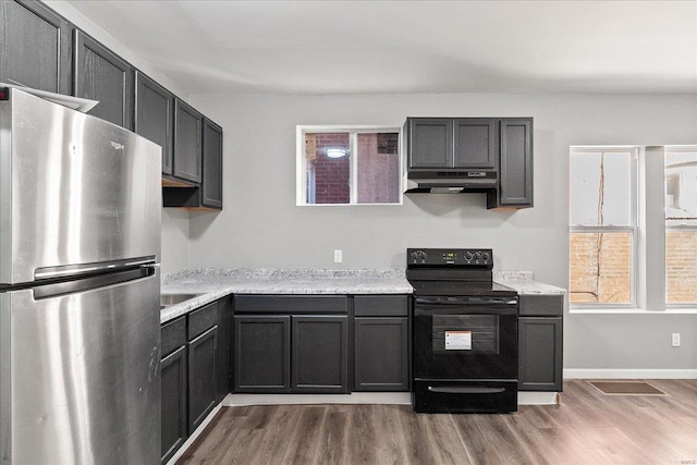 kitchen featuring light wood finished floors, black range with electric stovetop, freestanding refrigerator, and under cabinet range hood