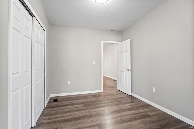 unfurnished bedroom featuring visible vents, a closet, baseboards, and wood finished floors