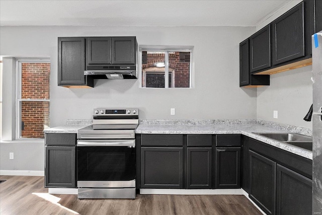 kitchen with baseboards, light countertops, stainless steel range with electric cooktop, light wood-type flooring, and under cabinet range hood