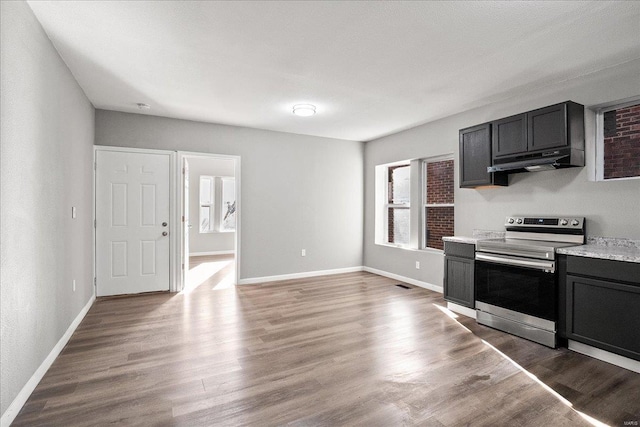 kitchen with under cabinet range hood, electric range, baseboards, light countertops, and light wood finished floors