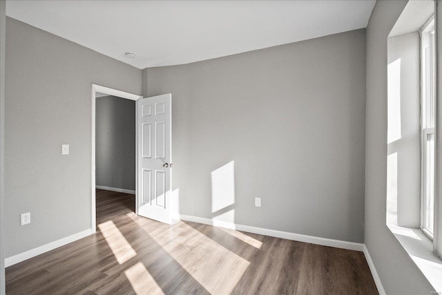 spare room featuring baseboards and wood finished floors