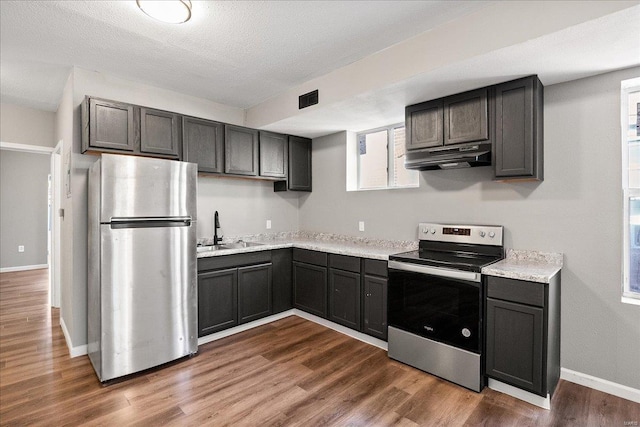 kitchen with under cabinet range hood, a sink, visible vents, appliances with stainless steel finishes, and dark wood finished floors