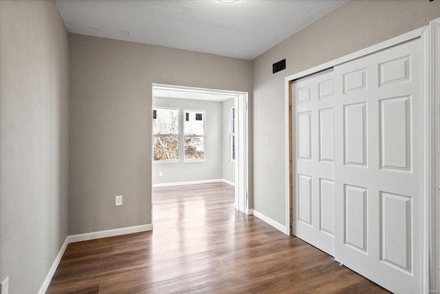 hallway featuring dark wood finished floors and baseboards