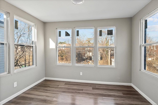 spare room featuring dark wood-style floors, plenty of natural light, and baseboards