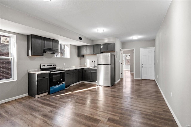 kitchen featuring dark wood finished floors, light countertops, appliances with stainless steel finishes, a sink, and under cabinet range hood