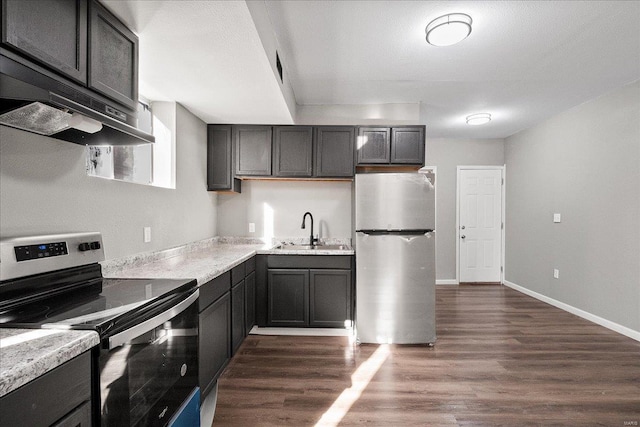 kitchen with baseboards, dark wood finished floors, stainless steel appliances, light countertops, and a sink