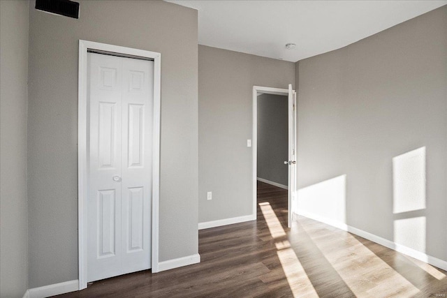 unfurnished bedroom featuring a closet, baseboards, and wood finished floors