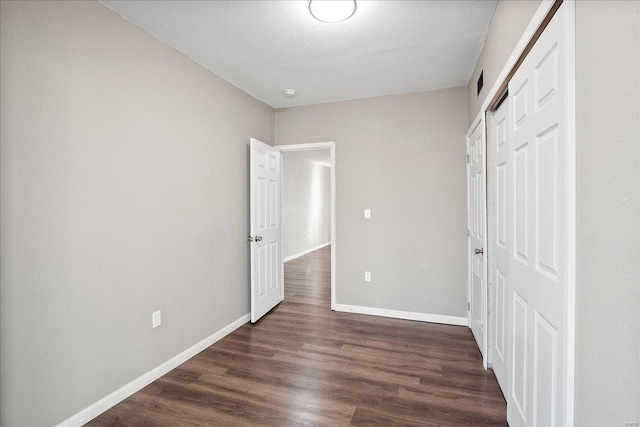 unfurnished bedroom featuring visible vents, baseboards, dark wood finished floors, and a closet