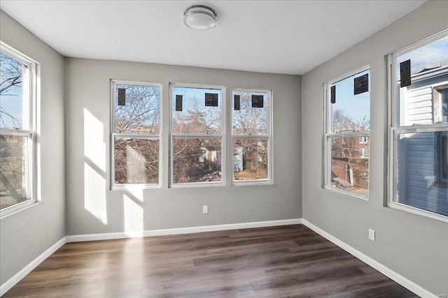 spare room with a healthy amount of sunlight and dark wood finished floors