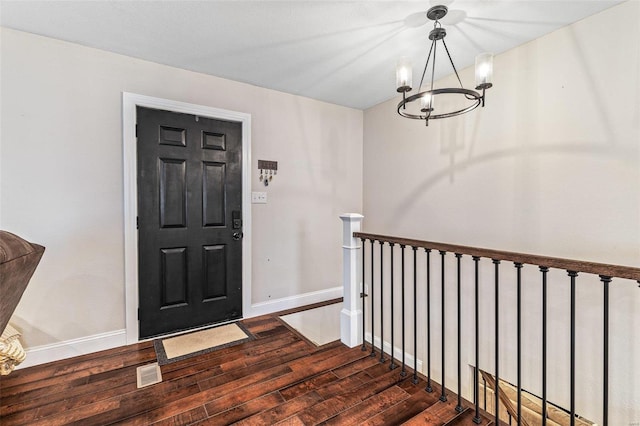 entryway with an inviting chandelier, dark wood finished floors, visible vents, and baseboards