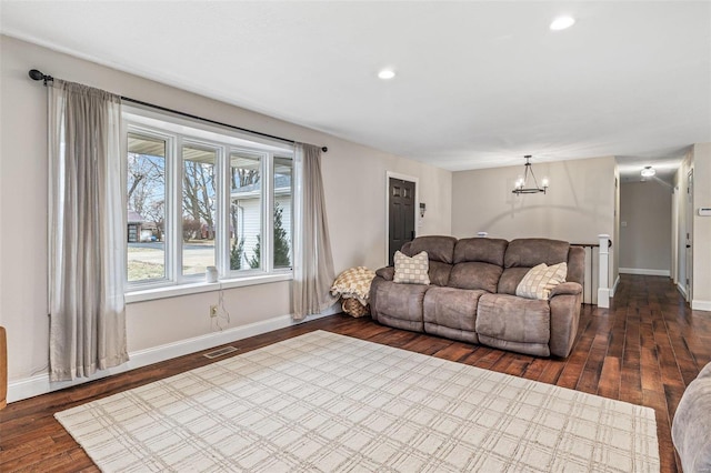 living room featuring dark wood-style floors, visible vents, baseboards, and an inviting chandelier