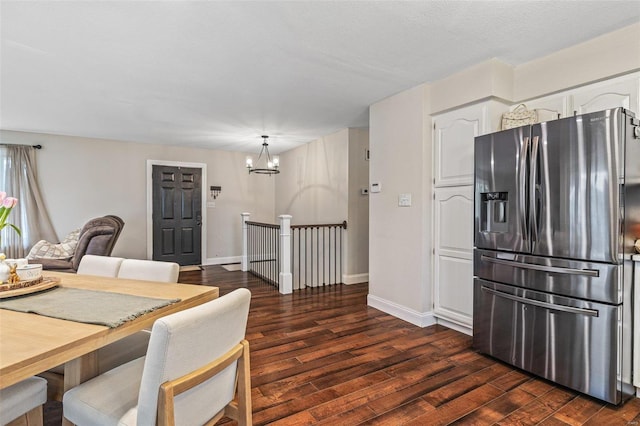 dining area featuring a chandelier, dark wood finished floors, and baseboards