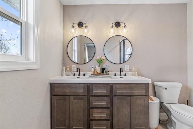 bathroom featuring a sink, toilet, and double vanity