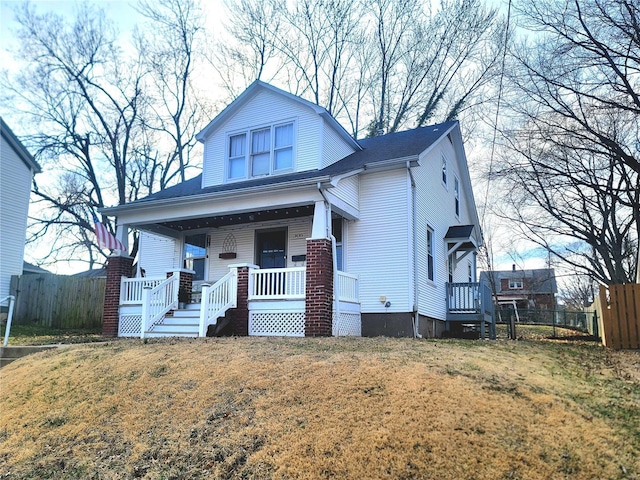 bungalow-style house with a front lawn, fence, and a porch