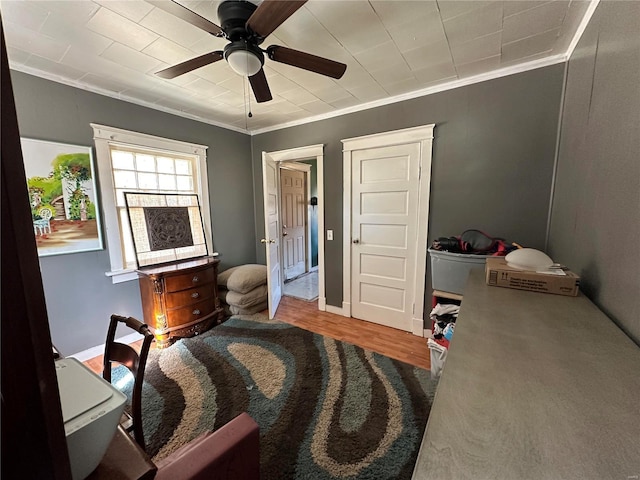 bedroom with wood finished floors, a ceiling fan, and crown molding