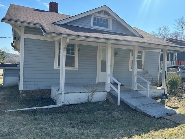 bungalow-style house with covered porch, a chimney, and roof with shingles