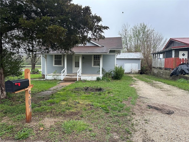 bungalow-style home with driveway, covered porch, and roof with shingles