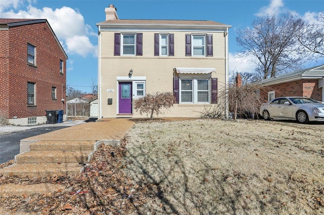 view of front of home with a chimney and brick siding