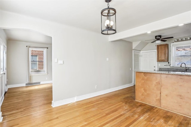 kitchen with a ceiling fan, light wood-type flooring, arched walkways, and baseboards