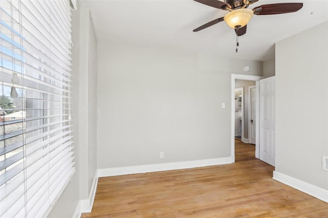 unfurnished room with light wood-type flooring, a ceiling fan, and baseboards