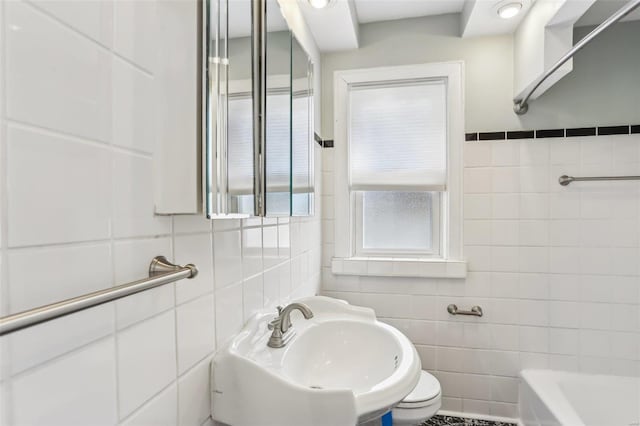 bathroom with a sink, tile walls, and a bathing tub