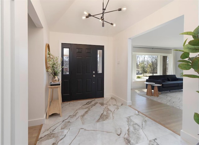 foyer with a chandelier, marble finish floor, vaulted ceiling, and baseboards