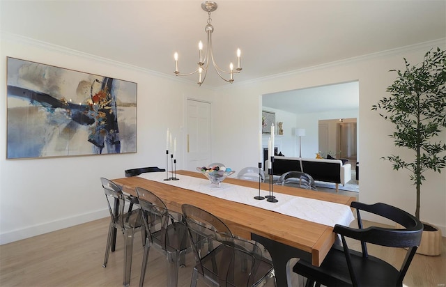 dining room with ornamental molding, light wood-type flooring, baseboards, and an inviting chandelier