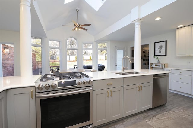 kitchen with vaulted ceiling with skylight, light countertops, stainless steel appliances, gray cabinetry, and a sink