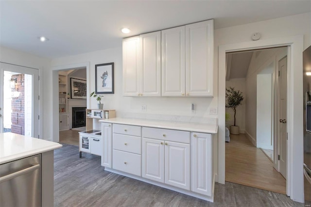 kitchen with stainless steel dishwasher, light wood-style flooring, white cabinets, and light countertops