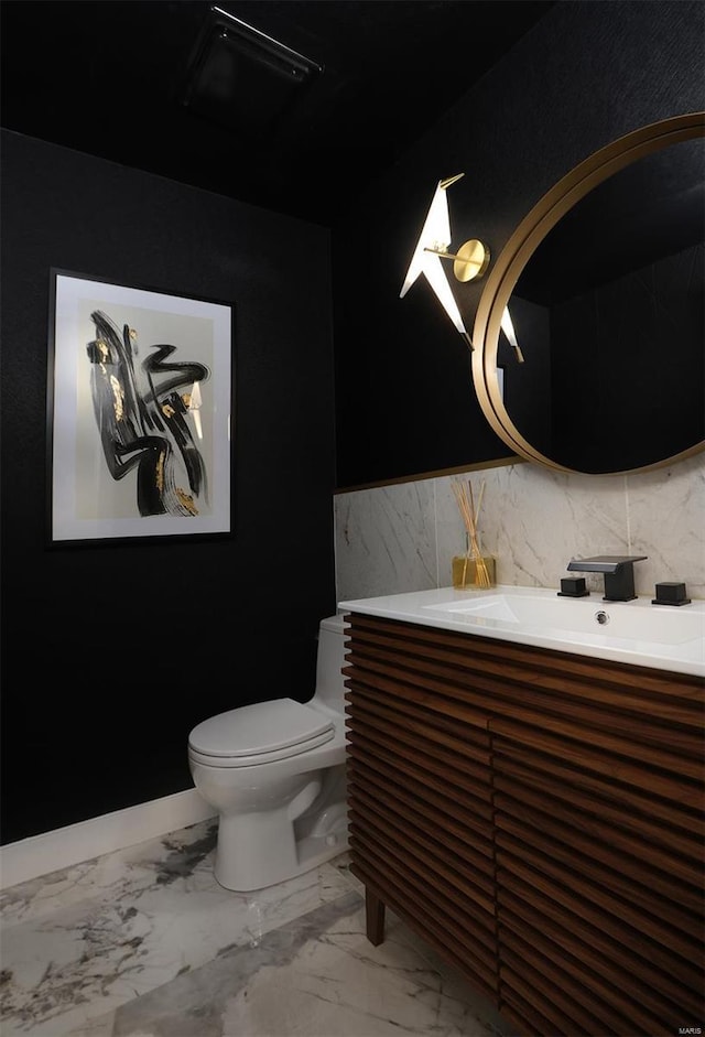 bathroom with marble finish floor, vanity, and toilet