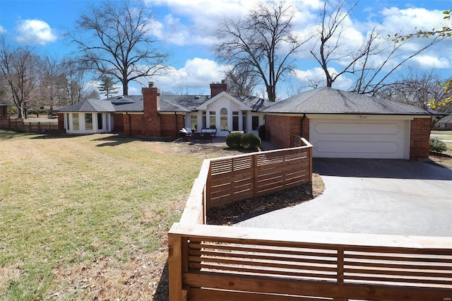 view of front of home featuring brick siding, a front lawn, an attached garage, and aphalt driveway