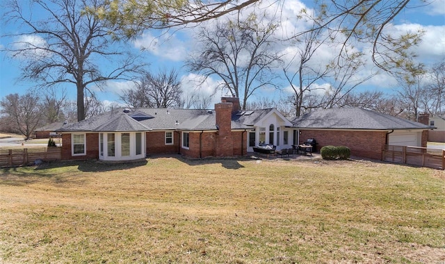 rear view of property with brick siding, a lawn, a chimney, and fence