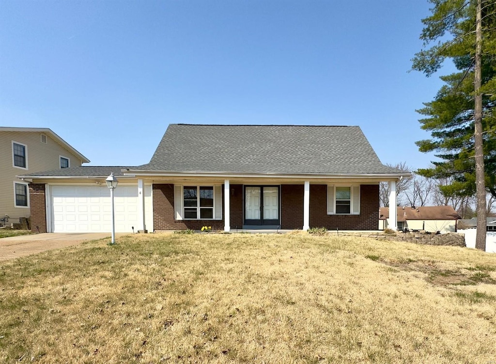 view of front of house with brick siding, a porch, concrete driveway, a front yard, and an attached garage