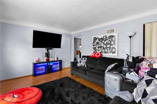 living area featuring visible vents and wood finished floors