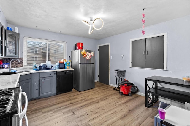 kitchen with black dishwasher, light countertops, light wood-style floors, freestanding refrigerator, and gas stove