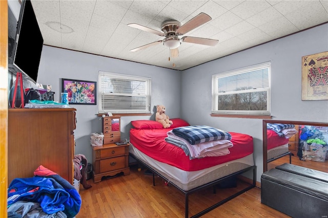 bedroom with multiple windows, a ceiling fan, and wood finished floors