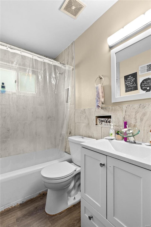 full bathroom featuring tile walls, visible vents, toilet, vanity, and wood finished floors