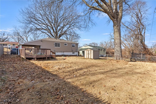 view of yard featuring a fenced backyard, an outdoor structure, a deck, and a shed