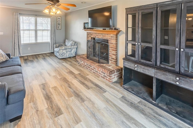 living area featuring a brick fireplace, a ceiling fan, ornamental molding, and wood finished floors