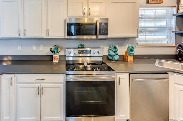 kitchen with dark countertops, white cabinetry, appliances with stainless steel finishes, and a sink