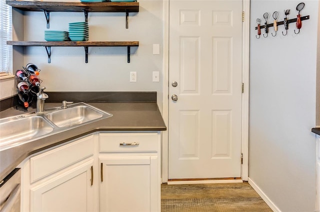 kitchen with open shelves, dark countertops, white cabinets, a sink, and dishwashing machine