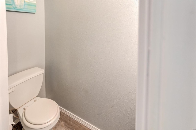 bathroom featuring a textured wall, wood finished floors, toilet, and baseboards