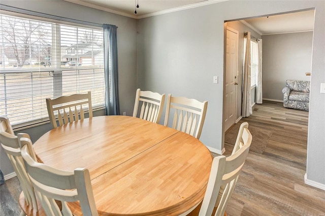 dining room featuring ornamental molding, baseboards, and wood finished floors