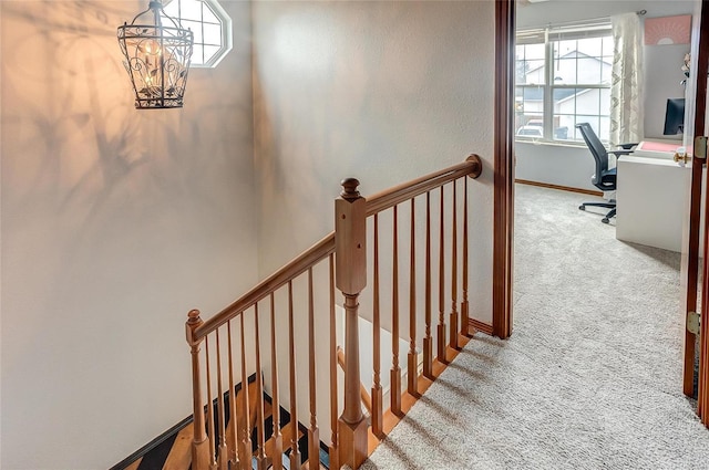 stairs with a chandelier, carpet flooring, and baseboards