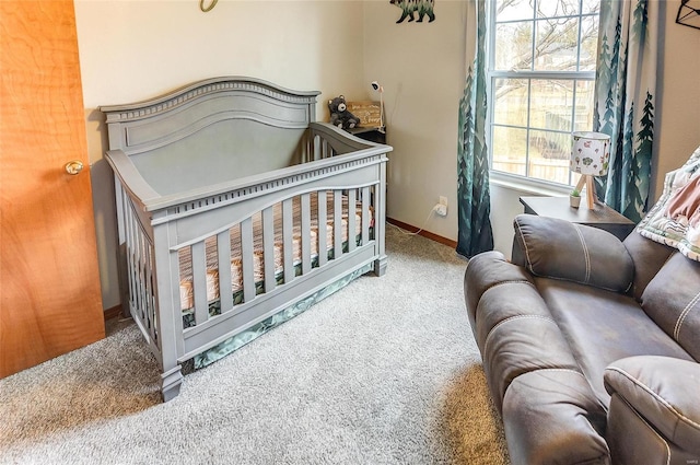 bedroom with a nursery area, baseboards, and carpet flooring