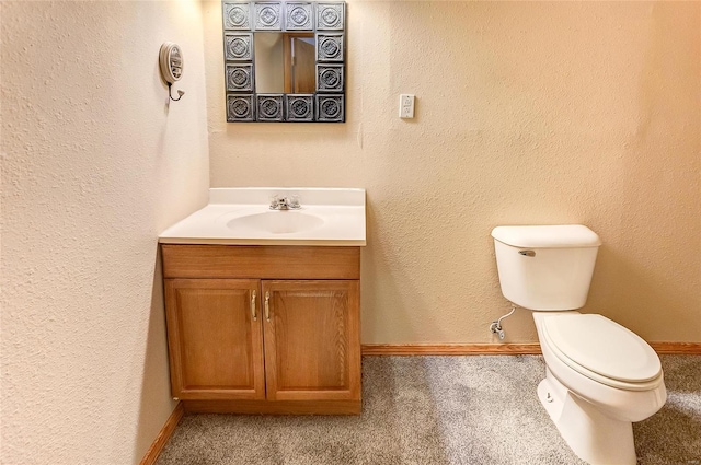 half bath with baseboards, a textured wall, vanity, and toilet