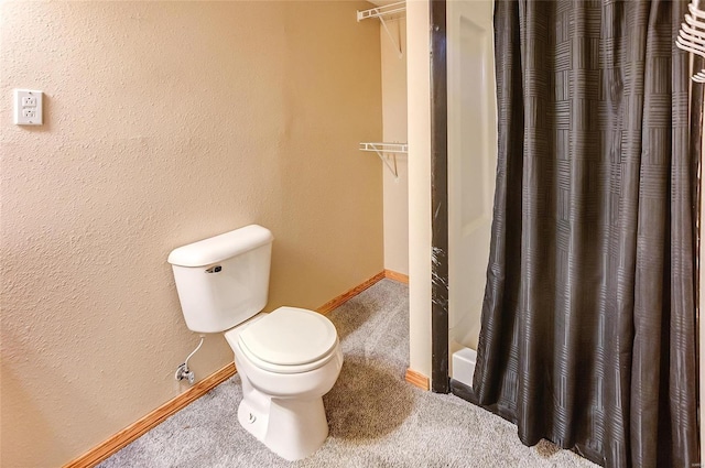 full bath with a shower with curtain, baseboards, a textured wall, and toilet