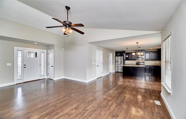 unfurnished living room featuring dark wood-type flooring, vaulted ceiling, and baseboards