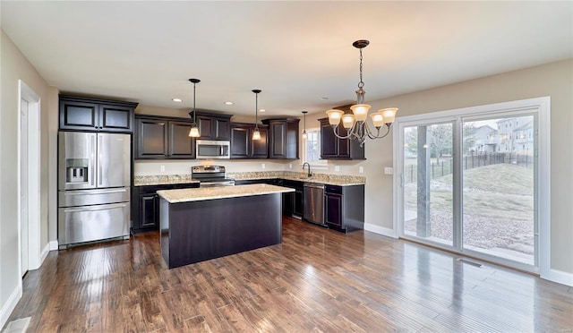 kitchen featuring an inviting chandelier, appliances with stainless steel finishes, dark wood-type flooring, a sink, and a kitchen island